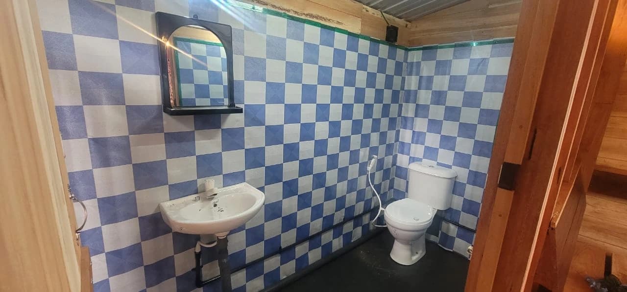 Modern bathroom with a shower, toilet, and sink, featuring white tiles and wooden accents.